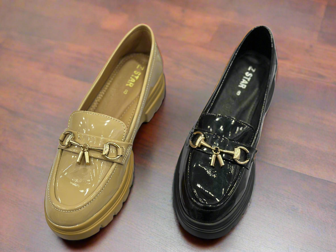 Pair of beige and black loafers with gold accents on a white background
